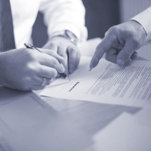 Two people reviewing and signing a document.