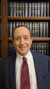 Smiling man in front of law books.
